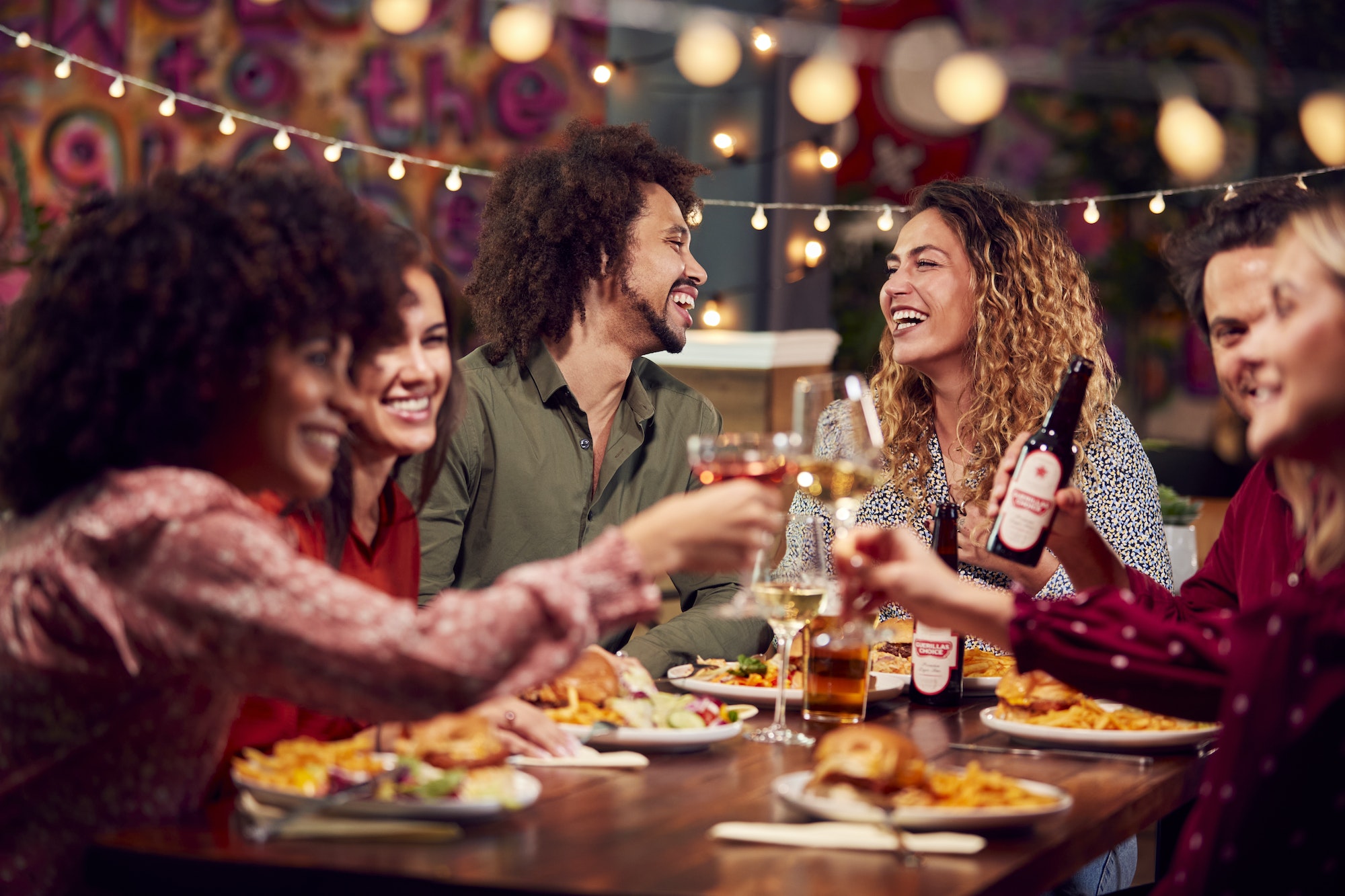 multi-cultural-group-of-friends-enjoying-night-out-eating-meal-and-drinking-in-restaurant-together.jpg